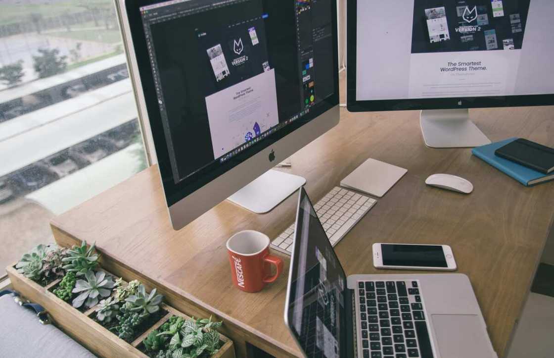 A desktop and laptop on a wooden desk