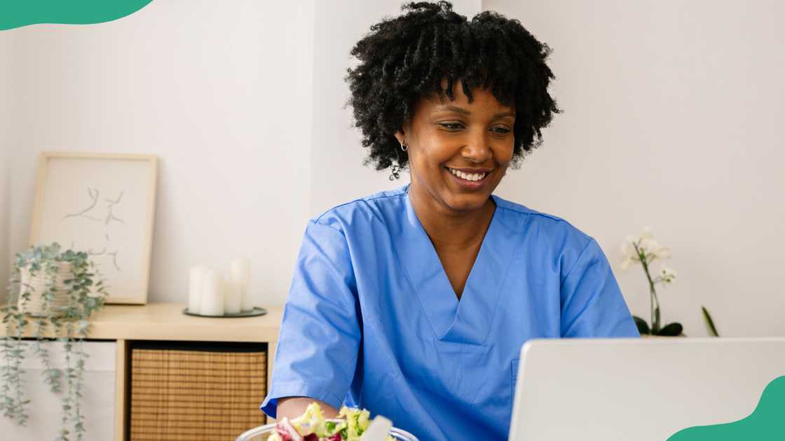 A nutritionist works on a laptop as she eats salad