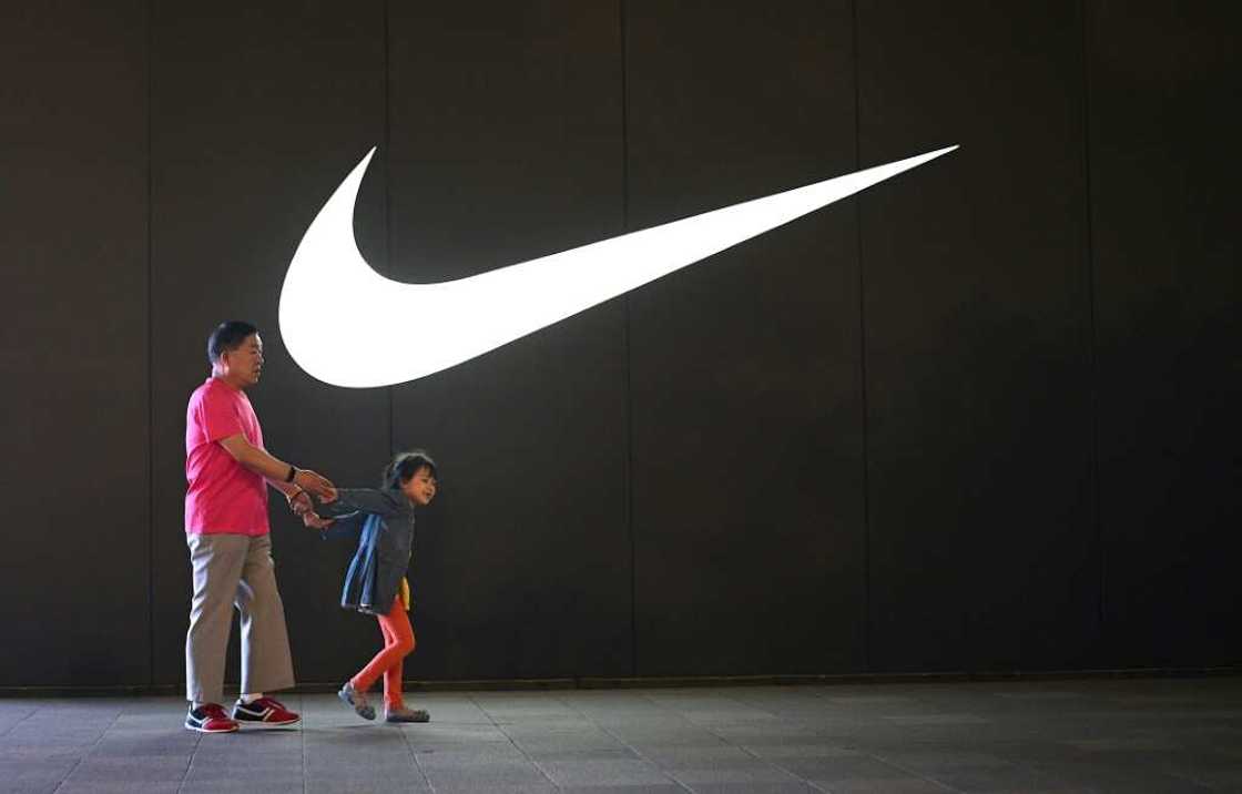 An elderly man and a child walk past a Nike logo in Wangfujing shopping district in Beijing in June 2021 An elderly man and a child walk past a Nike logo in Wangfujing shopping district in Beijing in June 2021