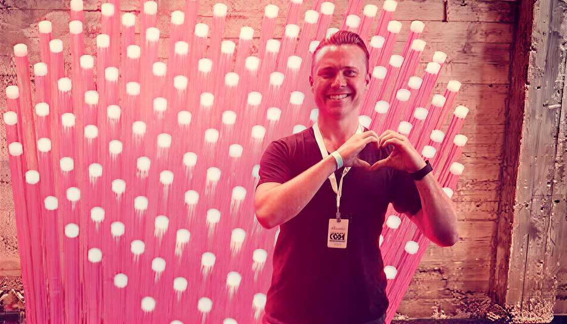 Bob Lee gestures a heart shape in front of pink heart shaped LED lights