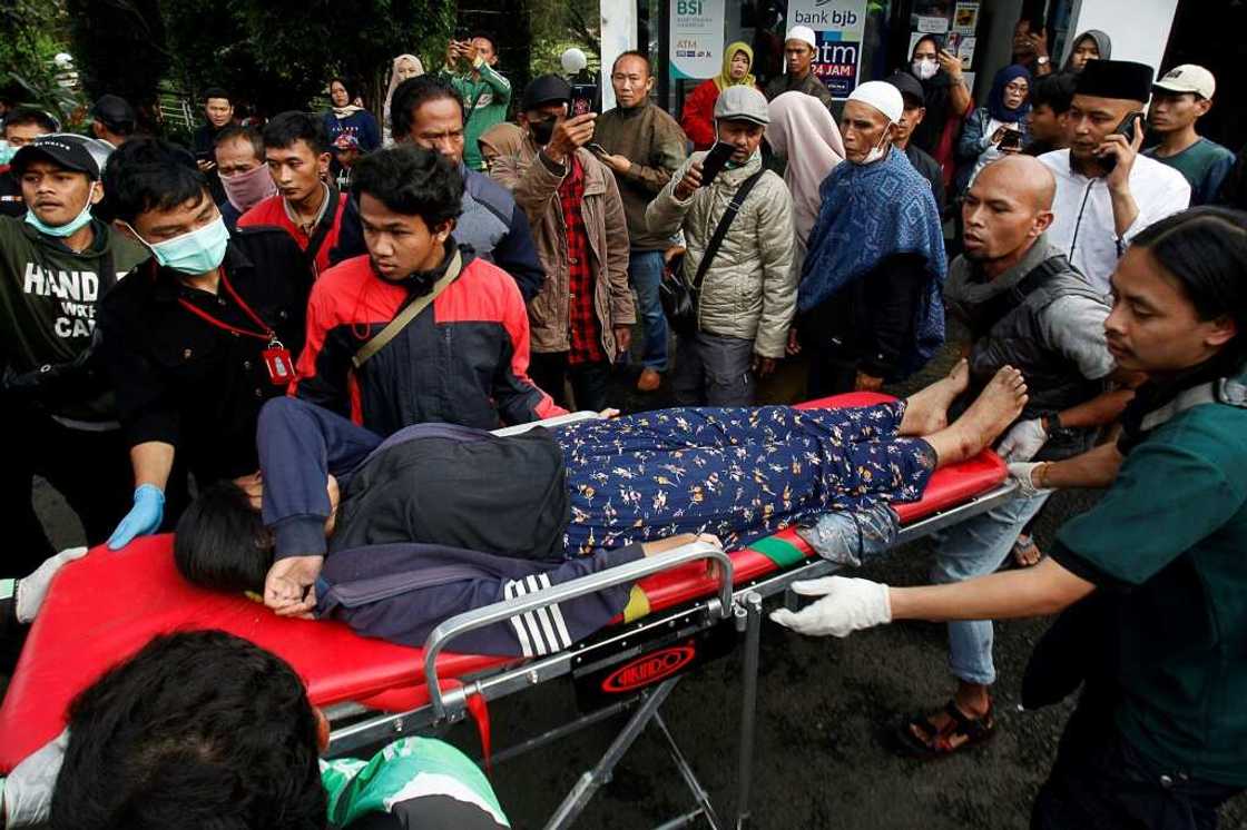 People evacuate a wounded woman on a stretcher following a landslide triggered by earthquake in Cianjur People evacuate a wounded woman on a stretcher following a landslide triggered by earthquake in Cianjur