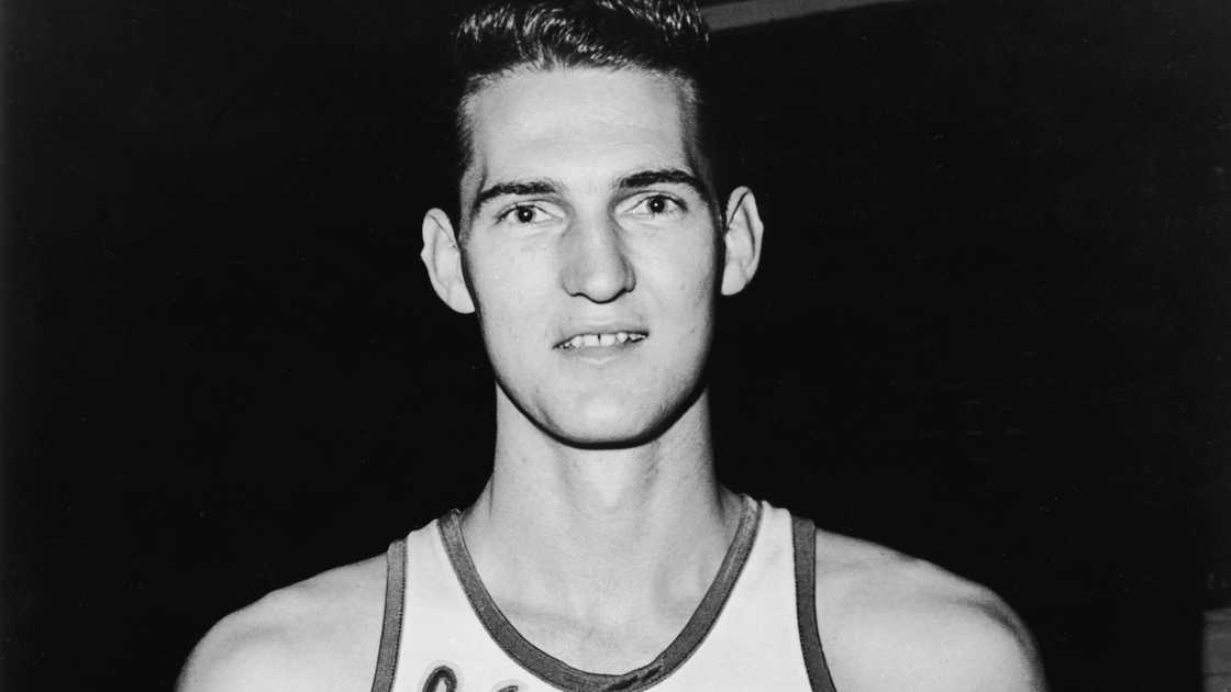 Jerry West poses in a Los Angeles Lakers uniform, holding a basketball.