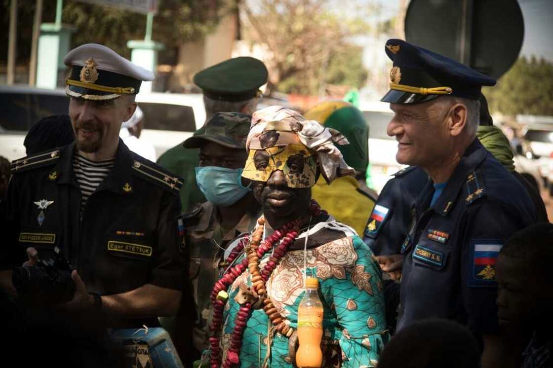 Russian military officers pose with a griot, a man in charge of singing praises, at a military parade in Mali Russian military officers pose with a griot, a man in charge of singing praises, at a military parade in Mali