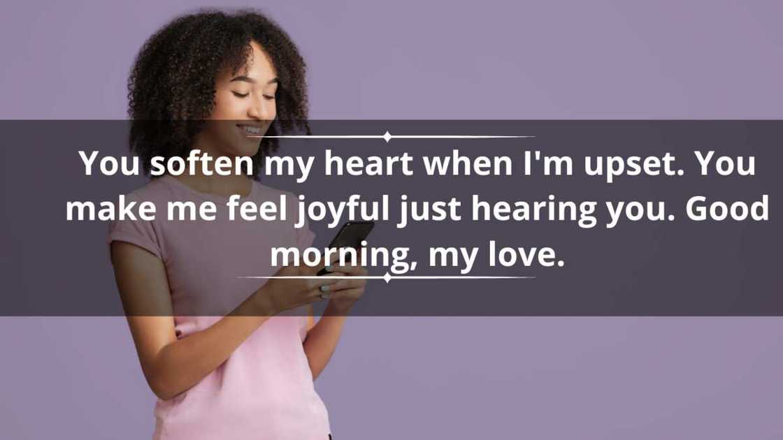 A happy woman in a pink tee reads a text from her phone A happy woman in a pink tee reads a text from her phone