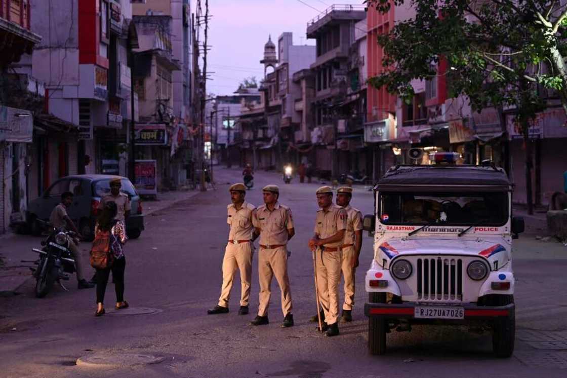 Police stand guard along a deserted street in Udaipur during a curfew imposed by authorities following the killing of Hindu tailor Kanhaiya Lal, allegedly by two Muslim men Police stand guard along a deserted street in Udaipur during a curfew imposed by authorities following the killing of Hindu tailor Kanhaiya Lal, allegedly by two Muslim men