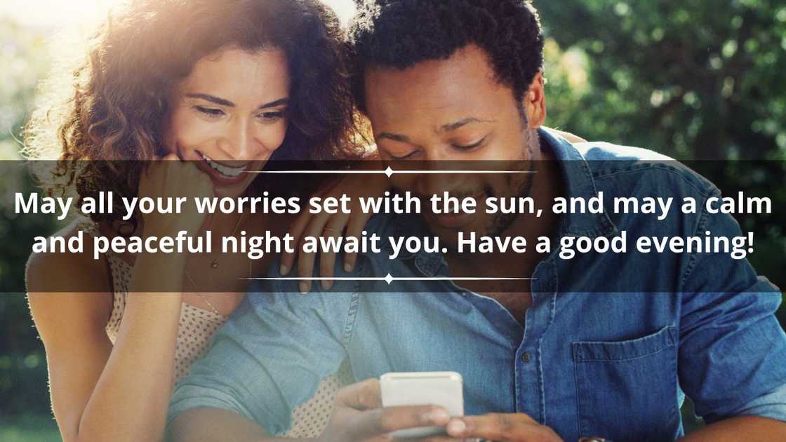 An affectionate young couple using a cellphone together while relaxing outdoors An affectionate young couple using a cellphone together while relaxing outdoors