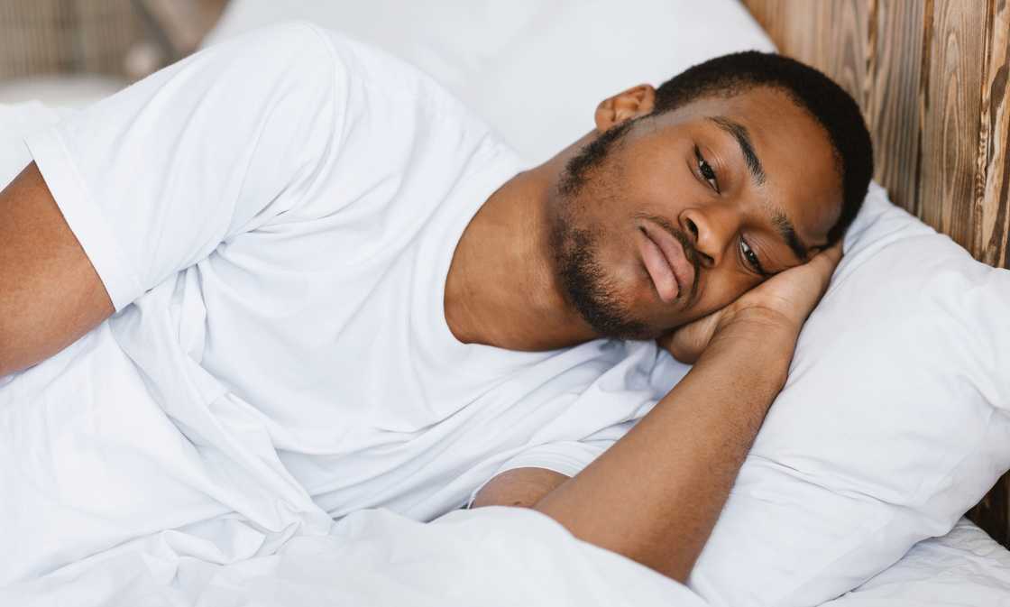 A depressed guy lying awake in bed having insomnia at night
