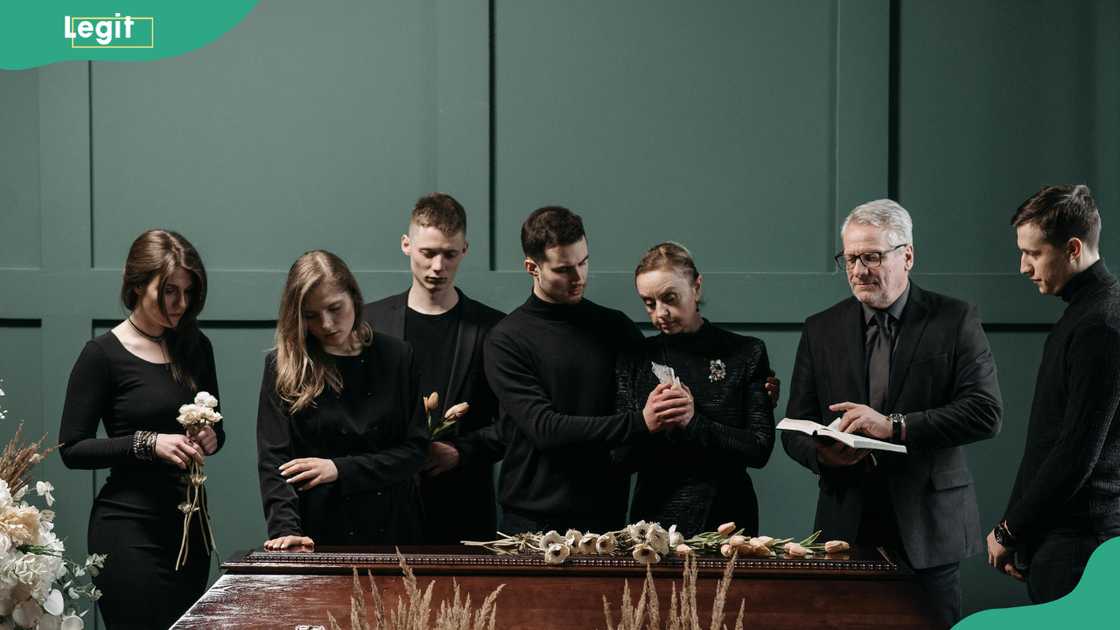 A family mourning in front of a casket and a pastor reading the bible