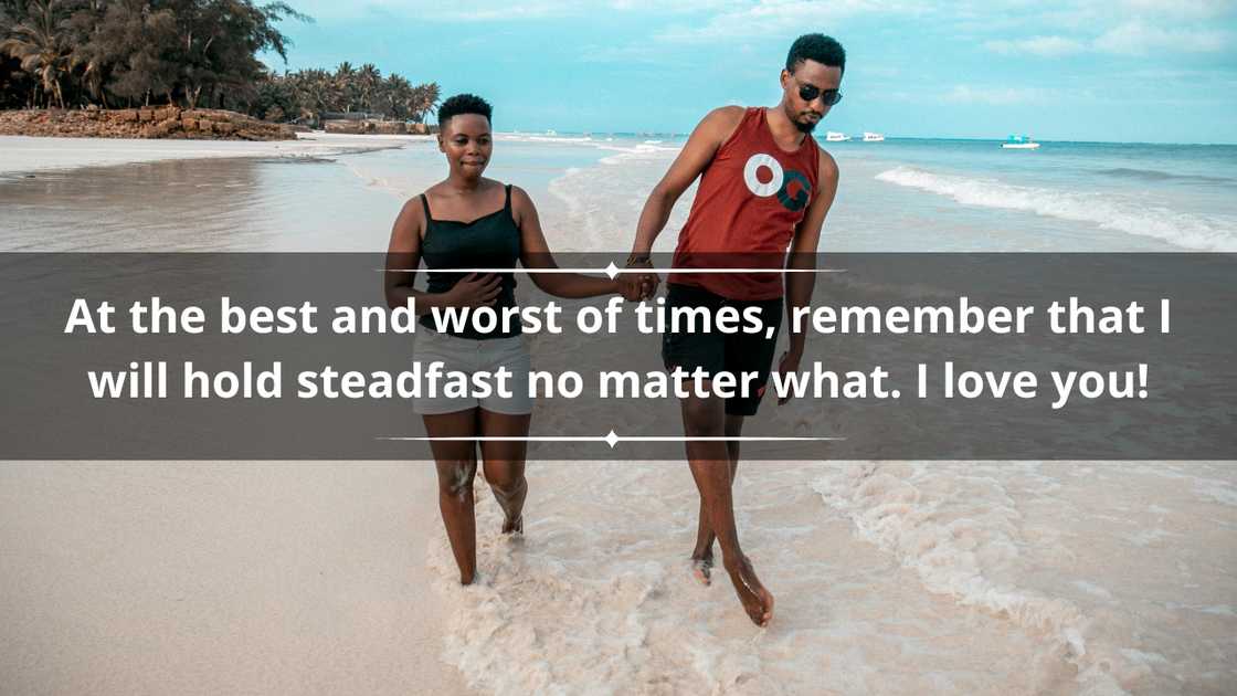 A young couple is pictured walking on a seashore while holding hands