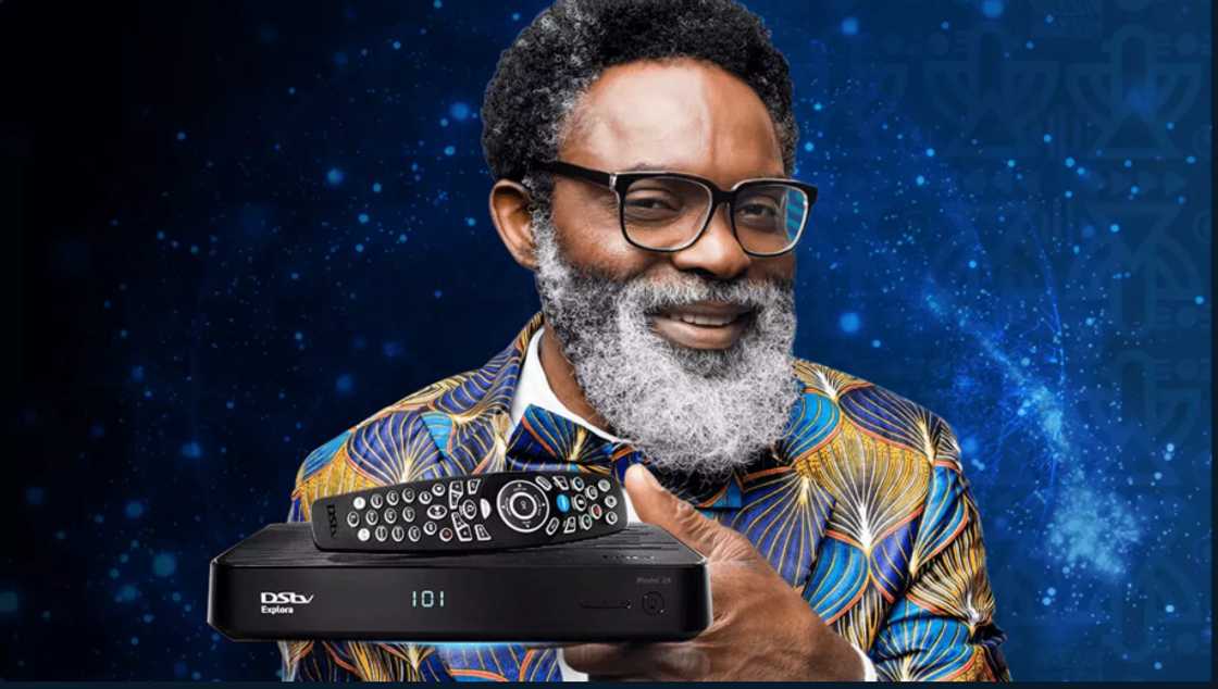 A man holding a DStv decoder and remote. A man holding a DStv decoder and remote.