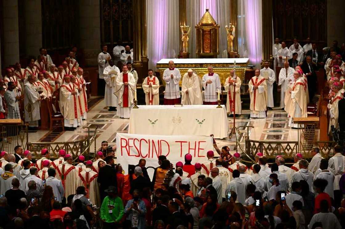 Indigenous people hold a protest banner calling for Pope Francis to rescind the Doctrine of Discovery, as he celebrates mass at the shrine of Sainte-Anne-de-Beaupre in Quebec, Canada, on July 28, 2022 Indigenous people hold a protest banner calling for Pope Francis to rescind the Doctrine of Discovery, as he celebrates mass at the shrine of Sainte-Anne-de-Beaupre in Quebec, Canada, on July 28, 2022