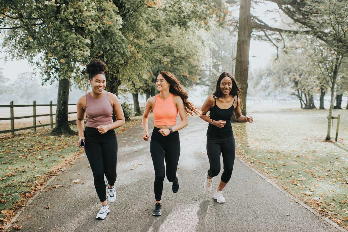 Three young ladies running through a sunny park