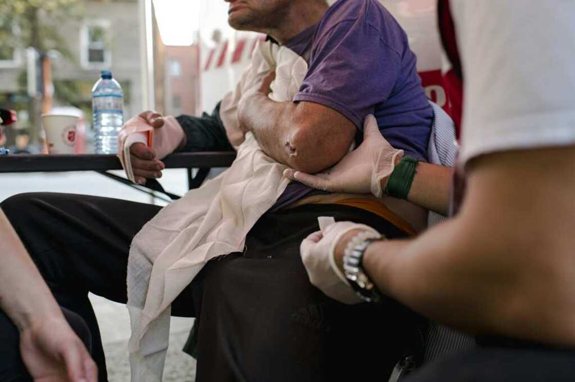 Aydin, director of emergency services and disaster assistance, offers a comforting hand to an injured homeless man as Bettina, a nurse, treats and checks his health in Montreal Aydin, director of emergency services and disaster assistance, offers a comforting hand to an injured homeless man as Bettina, a nurse, treats and checks his health in Montreal