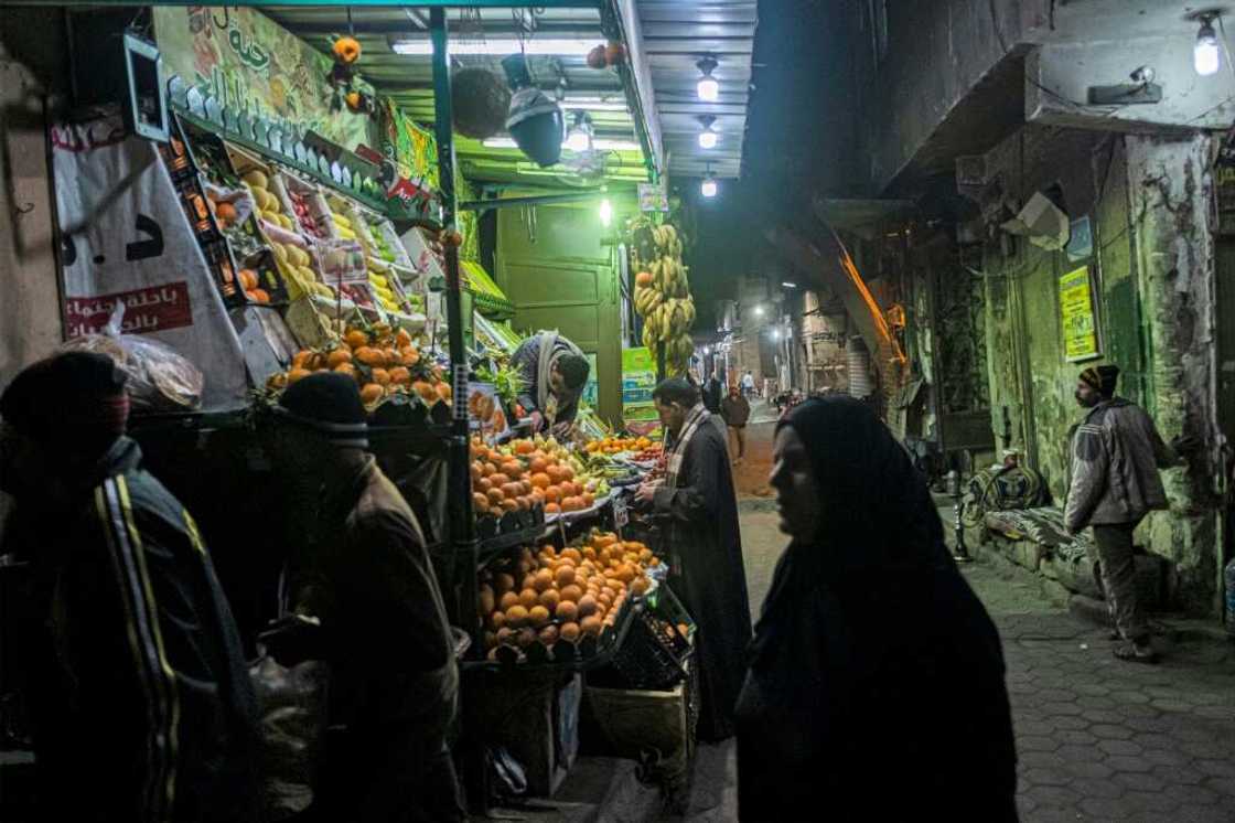 People walk past a fruit seller's stall in the Azhar district of Egypt's capital Cairo on January 16: many ordinary Egyptians are struggling amid an economic crisis People walk past a fruit seller's stall in the Azhar district of Egypt's capital Cairo on January 16: many ordinary Egyptians are struggling amid an economic crisis