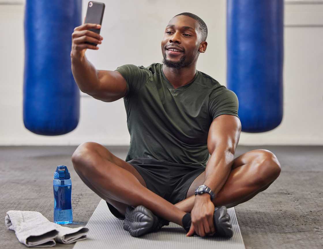 A man at the gym working out while on a video call.