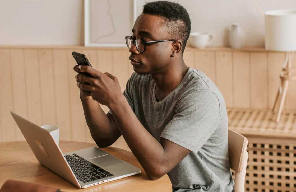 A young man sitting on his desk using a smartphone