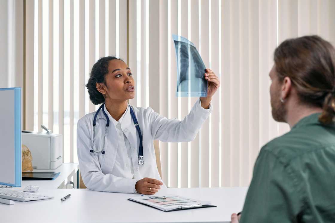 A woman in a white suit with a stethoscope, looking at an X-ray result