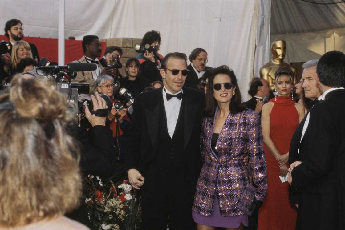 Kevin Costner, wearing a tuxedo and bow tie, and Cindy, who wears a checked purple jacket, attend the Academy Awards at the Shrine Auditorium in Los Angeles Kevin Costner, wearing a tuxedo and bow tie, and Cindy, who wears a checked purple jacket, attend the Academy Awards at the Shrine Auditorium in Los Angeles