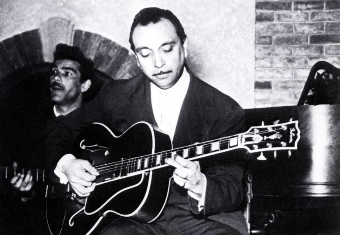 A black and white photo of Django Reinhardt playing guitar