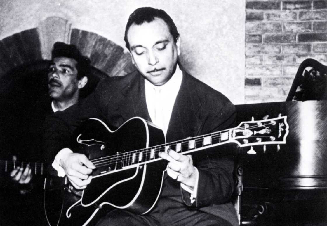 A black and white photo of Django Reinhardt playing guitar A black and white photo of Django Reinhardt playing guitar