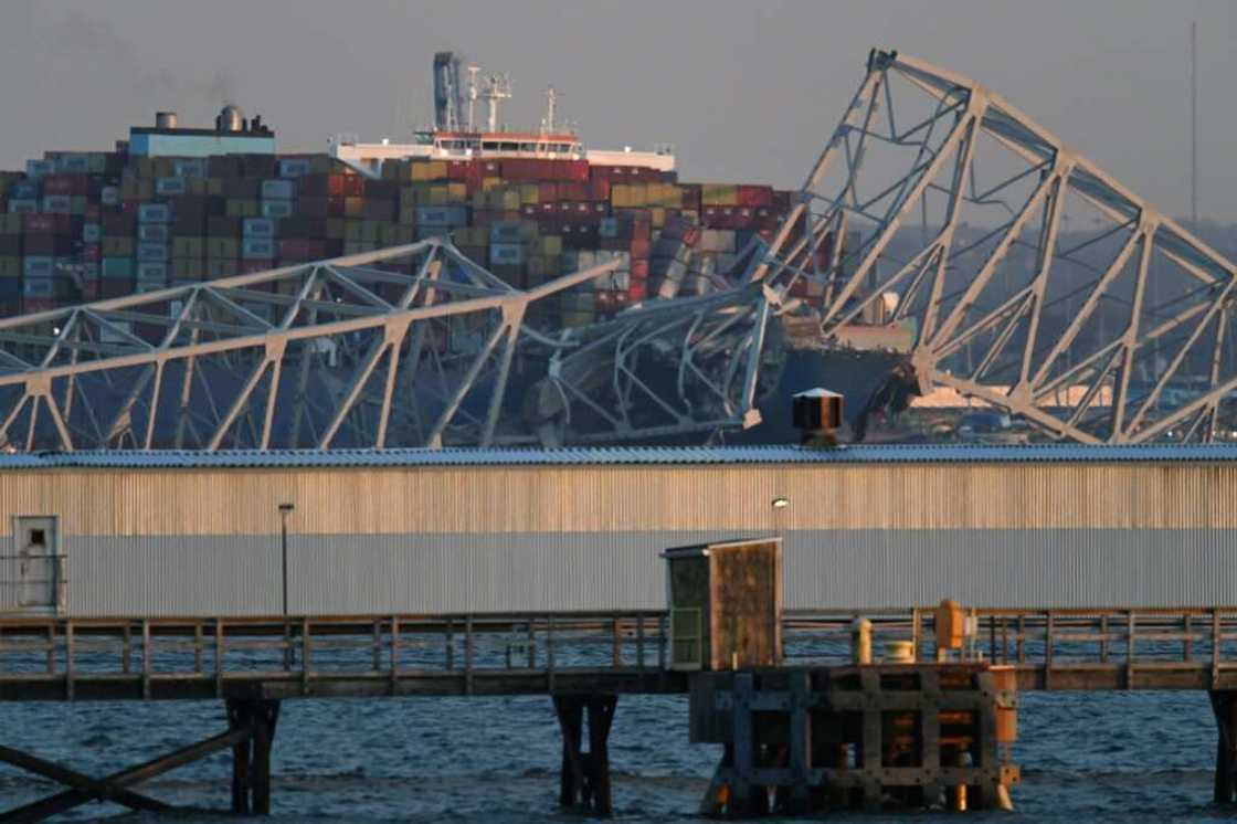 The steel frame of the Francis Scott Key Bridge sits on top of a container ship after it struck the bridge in Baltimore, Maryland, on March 26, 2024