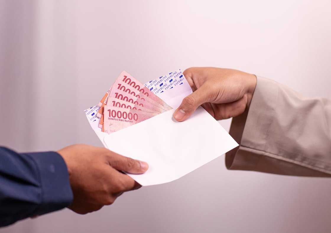 Hands exchanging an envelope filled with cash.