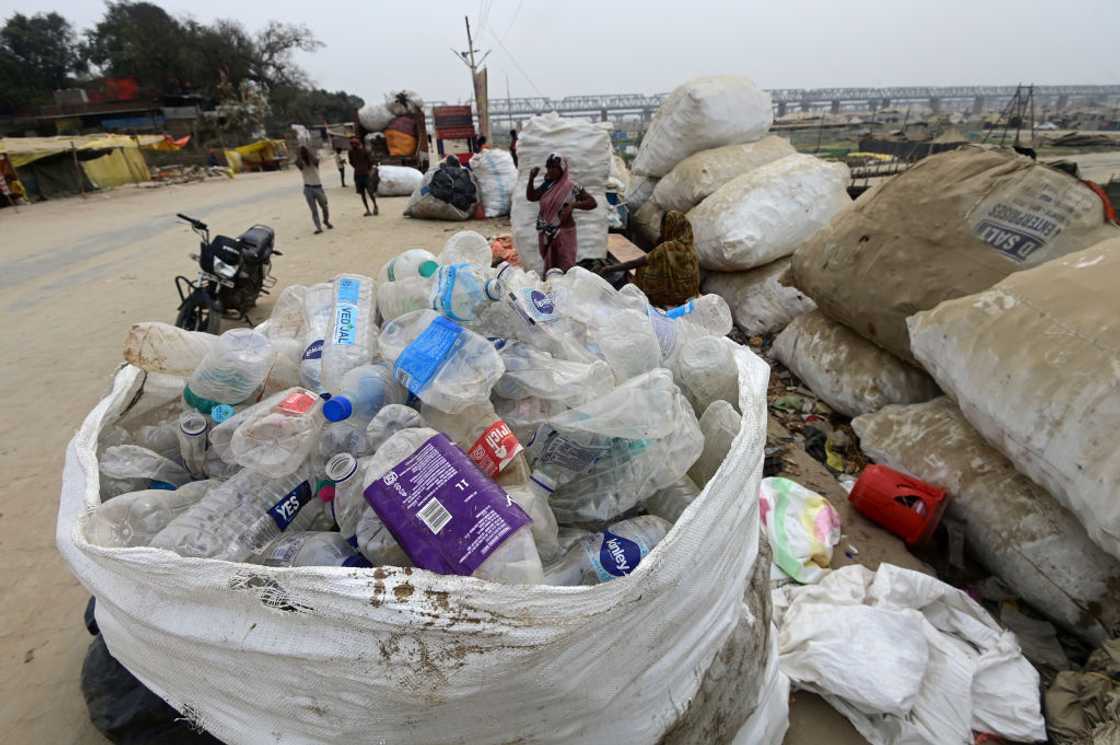 Rag pickers sit near discarded plastic bottles.