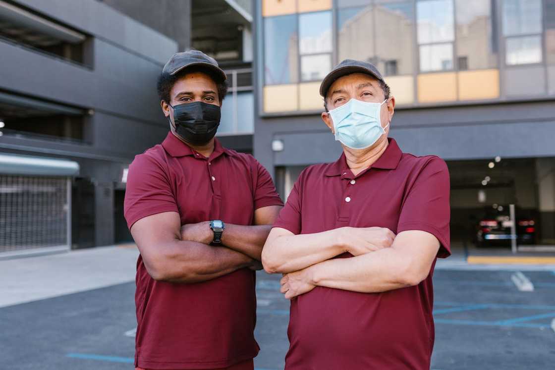 Two delivery workers standing outside a building wearing masks.