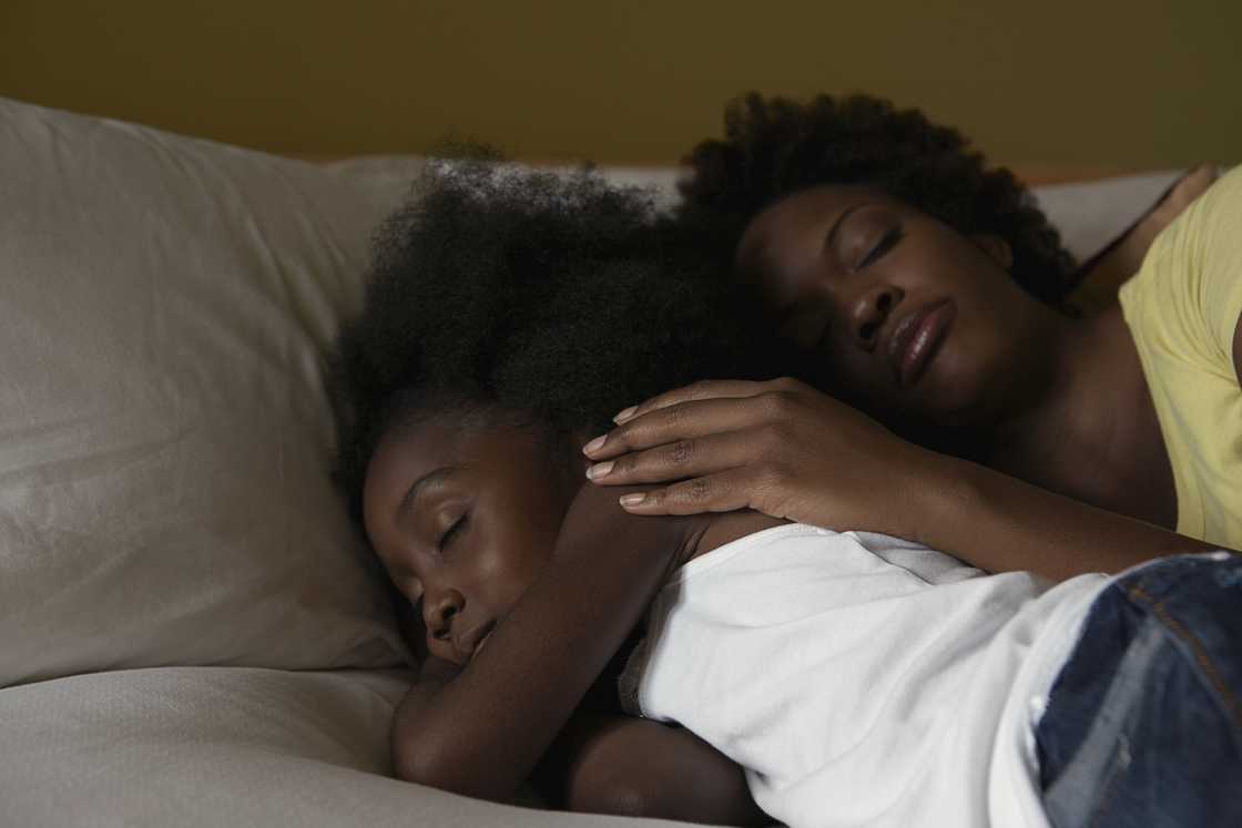 A mother hugging her daughter goodnight.