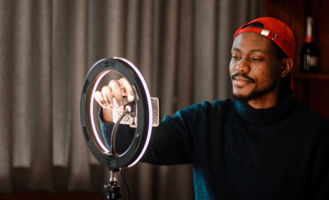 A YouTube influencer adjusts his ring-light and smartphone while vlogging. A YouTube influencer adjusts his ring-light and smartphone while vlogging.
