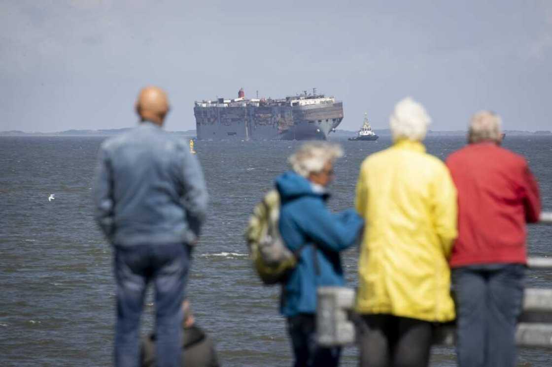 Dozens of people turned out to watch the ship being towed into port Dozens of people turned out to watch the ship being towed into port