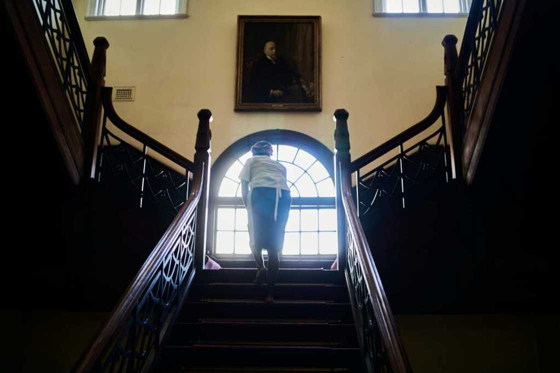 A cleaner works under a portrait of the queen in the Bulawayo Club, a former gentleman's retreat in the Bulawayo, Zimbabwe's second largest city