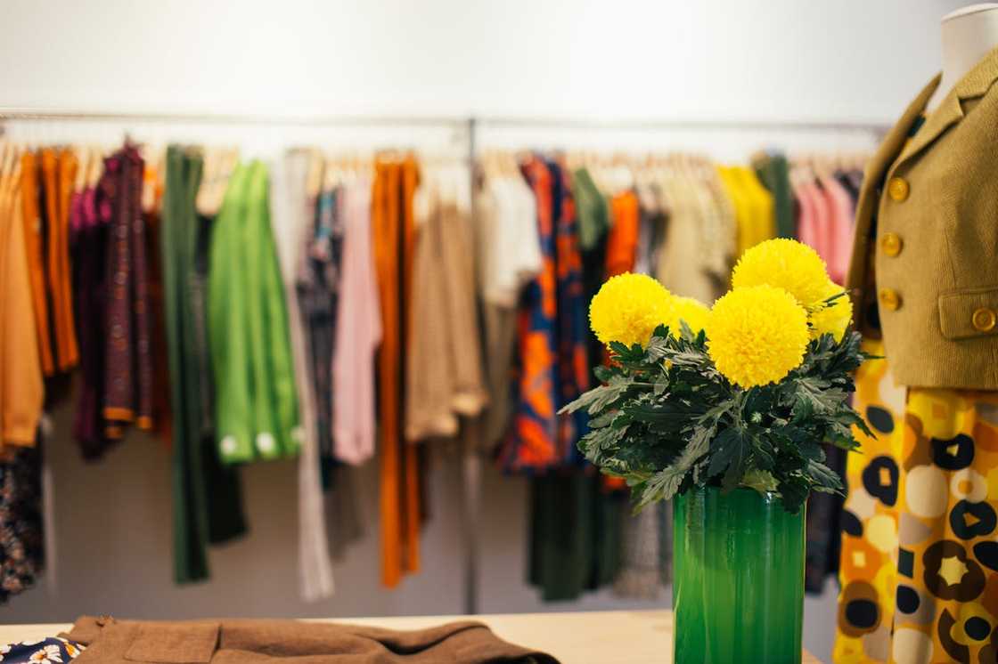 Yellow flowers in a green vase inside a colourful clothing boutique. Yellow flowers in a green vase inside a colourful clothing boutique.