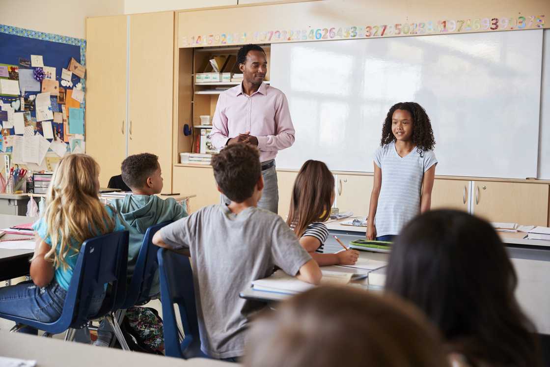 A teacher and pupil standing together before applauding audience.