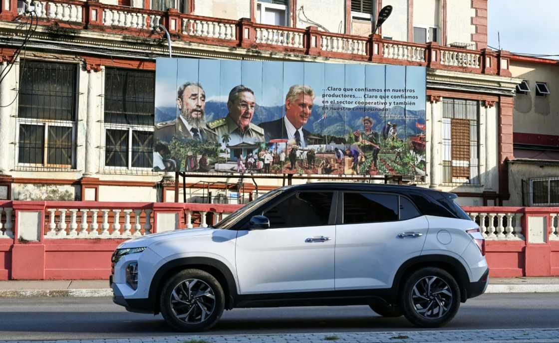 Un SUV circule devant une affiche représentant le chef de la révolution cubaine, Fidel Castro, son frère et ex-dirigeant Raul Castro et le président Miguel Diaz-Canel, à La Havane, le 5 septembre 2024