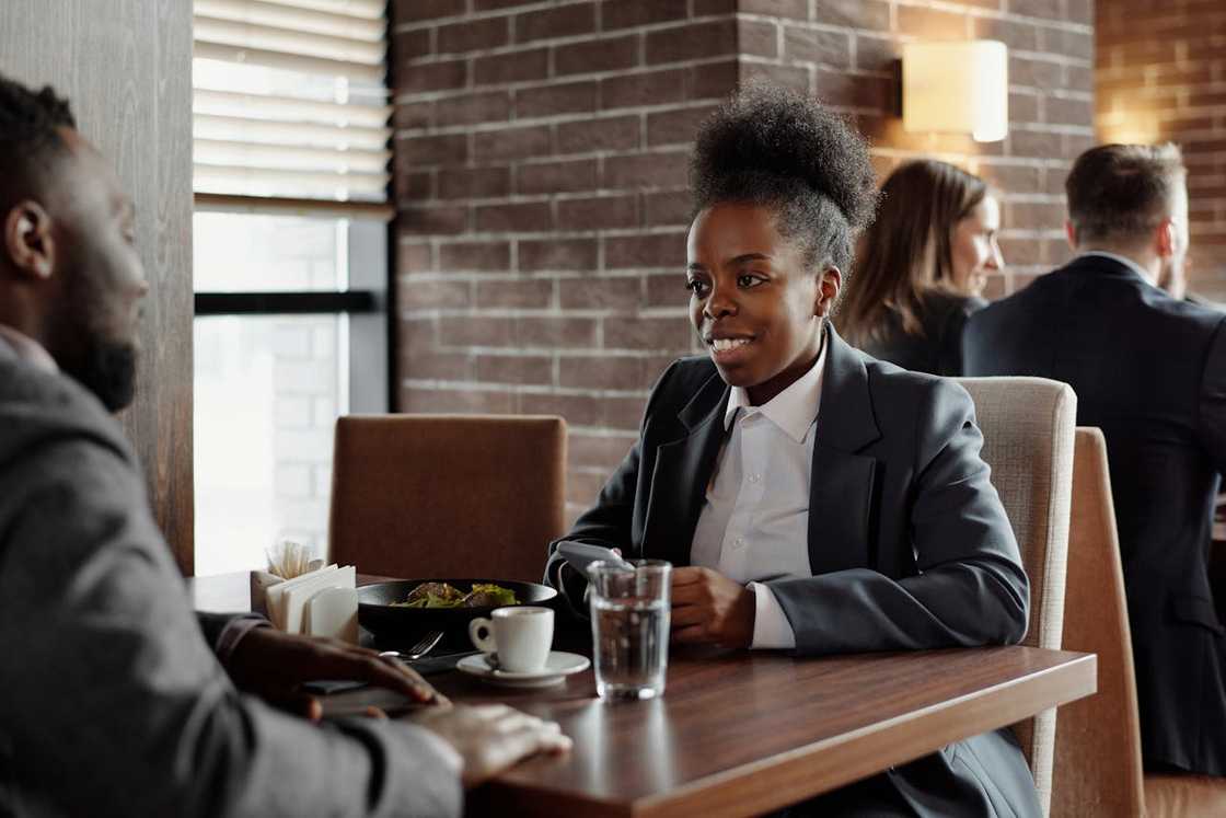 A man and woman talk privately in a lounge.
