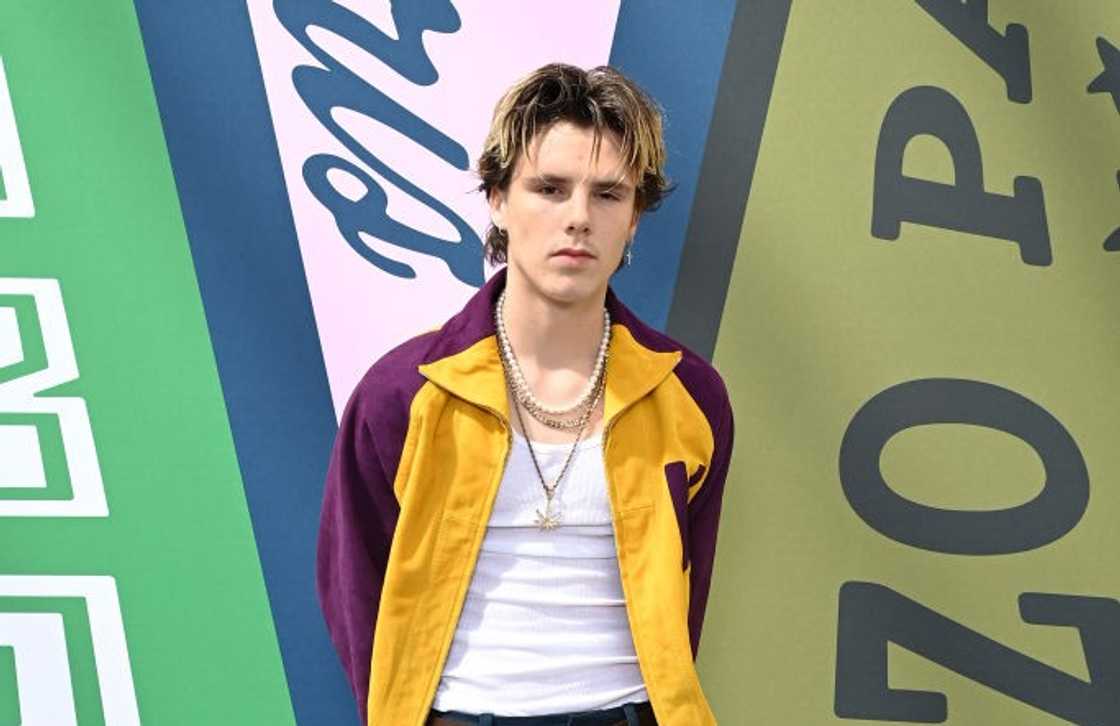 Cruz Beckham pose in a white vest, purple and yellow jacket at Paris Fashion Week Cruz Beckham pose in a white vest, purple and yellow jacket at Paris Fashion Week
