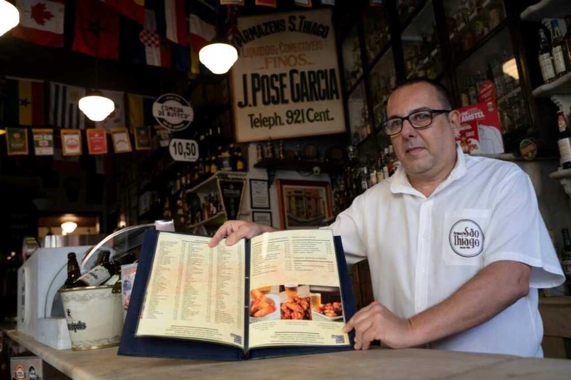 Carlos Fionda, 59, manager of Amazem Sao Thiago bar, shows of the physical menu at the Lapa neighborhood in Rio de Janeiro, Brazil, in May 2023.