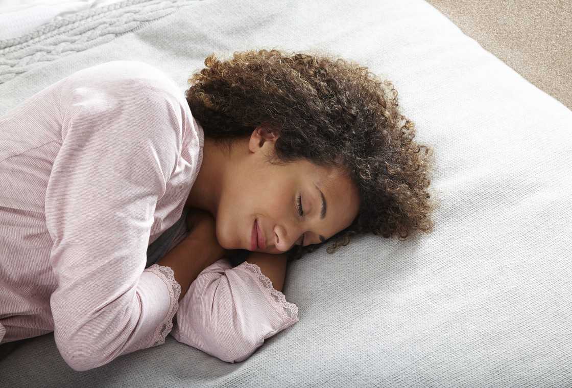 A woman sleeping on a white surface A woman sleeping on a white surface