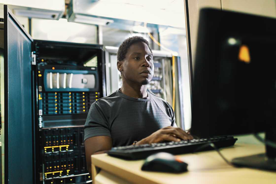System administration, man is working in data center with laptop System administration, man is working in data center with laptop