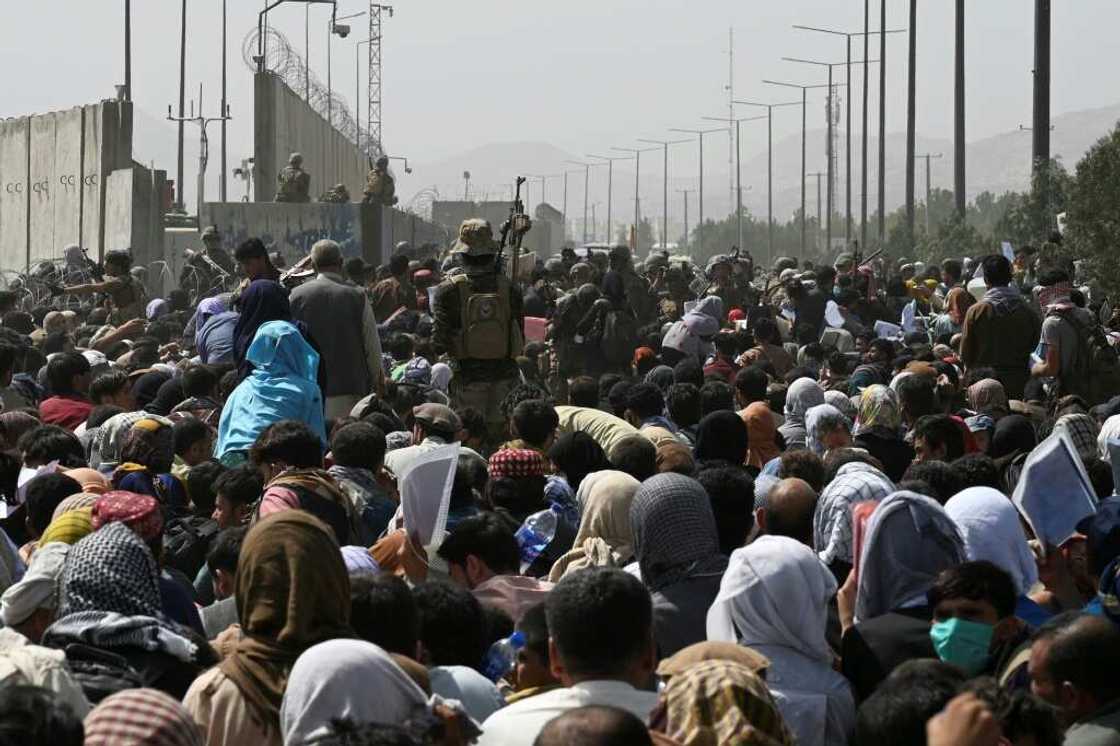 Afghans gather on a roadside near the military part of the airport in Kabul on August 20, 2021, hoping to flee from the country after the Taliban's military takeover of Afghanistan Afghans gather on a roadside near the military part of the airport in Kabul on August 20, 2021, hoping to flee from the country after the Taliban's military takeover of Afghanistan