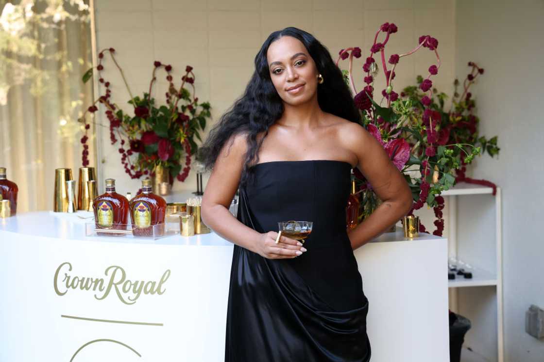 Solange Knowles poses in a black dress holing a drink Solange Knowles poses in a black dress holing a drink