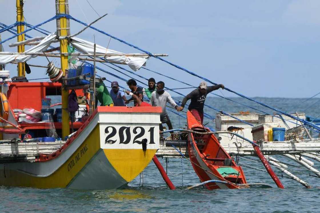 Crew members prepare to load small boats to their fishing 'mother' boat before heading into the South China Sea Crew members prepare to load small boats to their fishing 'mother' boat before heading into the South China Sea