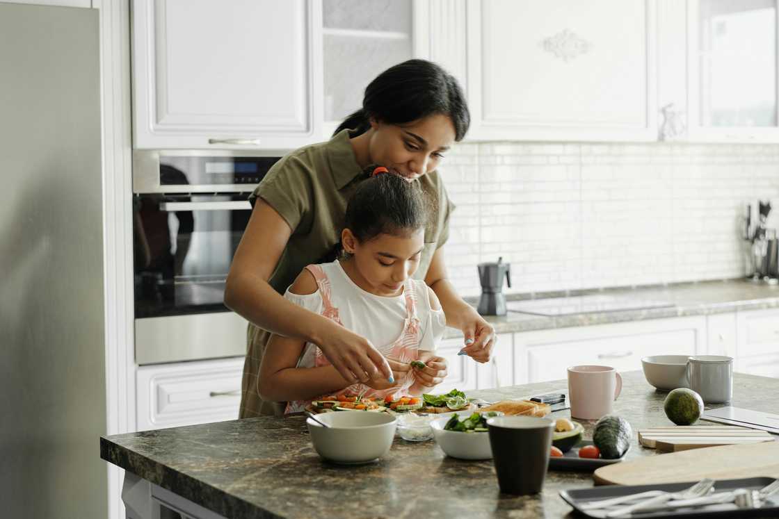 A woman cooking with a young child in the kitchen A woman cooking with a young child in the kitchen
