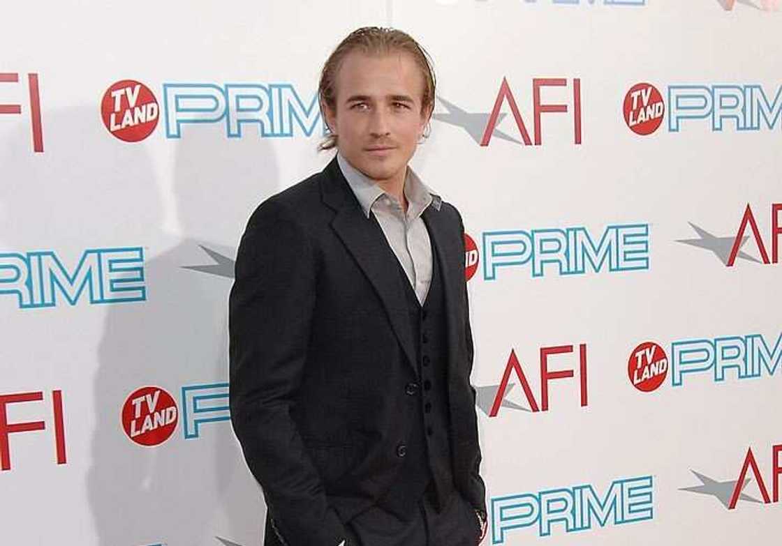 Jesse Wayne Johnson posing for a photo in a black suit and a white shirt