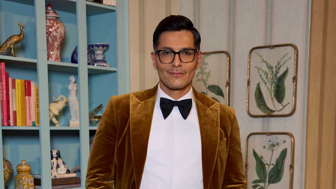 Rodrigo Reyes poses standing for a portrait in a golden velvet suit. Rodrigo Reyes poses standing for a portrait in a golden velvet suit.