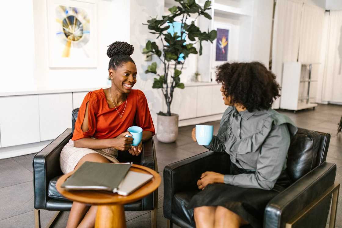 Two women smiling and chatting over coffee in a relaxed setting.