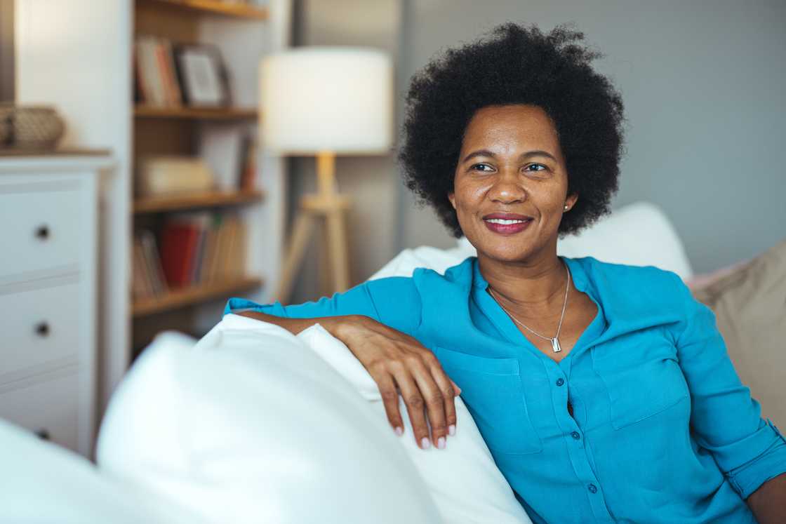 A happy mature woman smiling while sitting on a sofa at home A happy mature woman smiling while sitting on a sofa at home