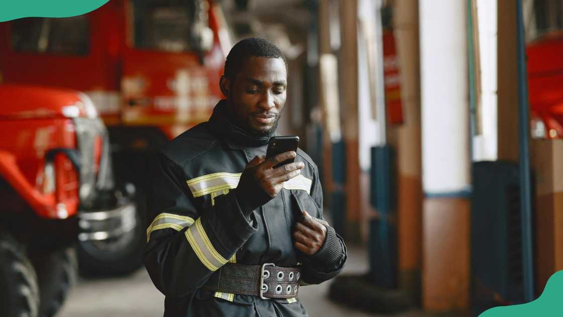 A man standing near a fire truck is busy using his cellphone