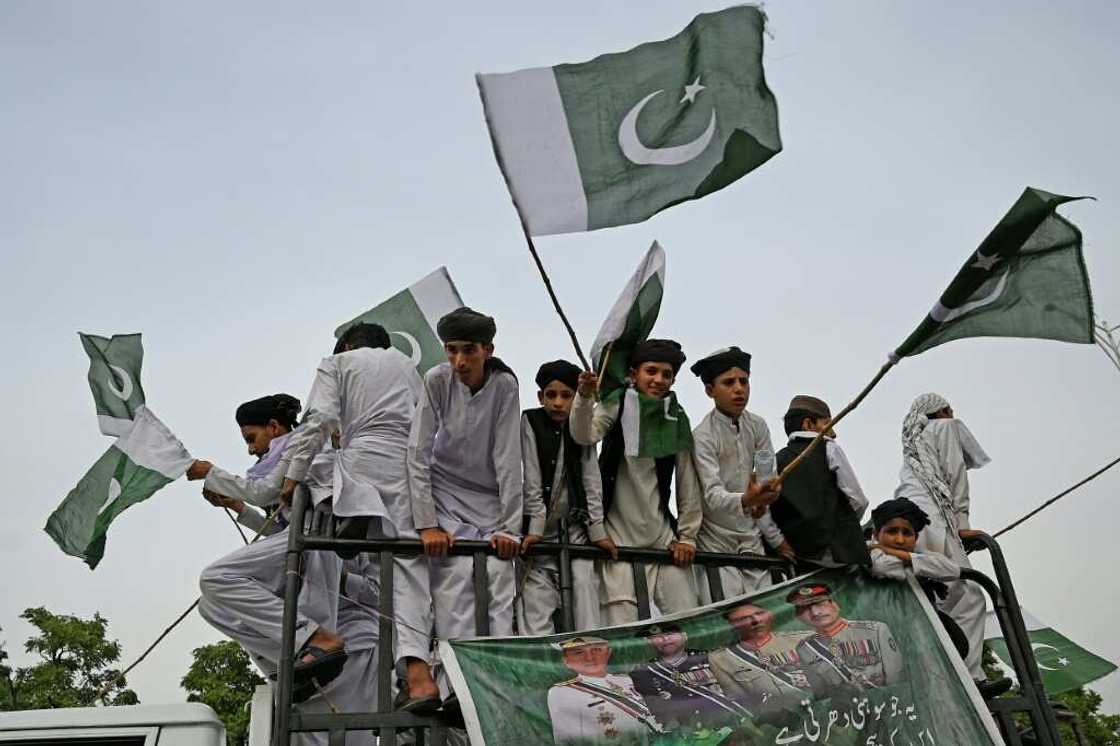 People carry flags at a rally to show solidarity with Pakistan's army in Islamabad. An economic crisis is driving Imran Khan's campaign to return to power, as ordinary people say they are unable to feed their families